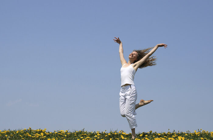 Smiling girl dancing in dandelion field